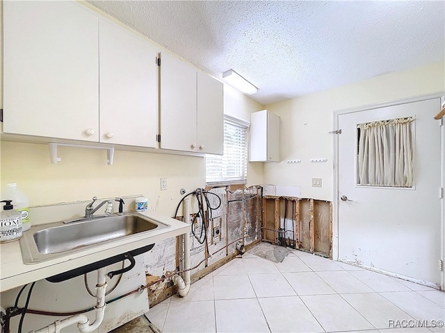 kitchen featuring sink, light tile patterned floors, white cabinets, and a textured ceiling