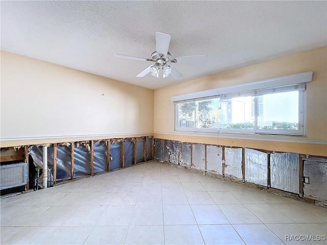 empty room with ceiling fan, plenty of natural light, and a textured ceiling