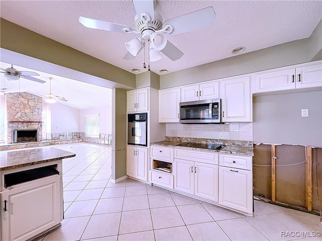 kitchen featuring stone countertops, stainless steel appliances, white cabinets, and light tile patterned flooring