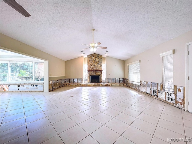 unfurnished living room with a stone fireplace, vaulted ceiling, a textured ceiling, and light tile patterned floors