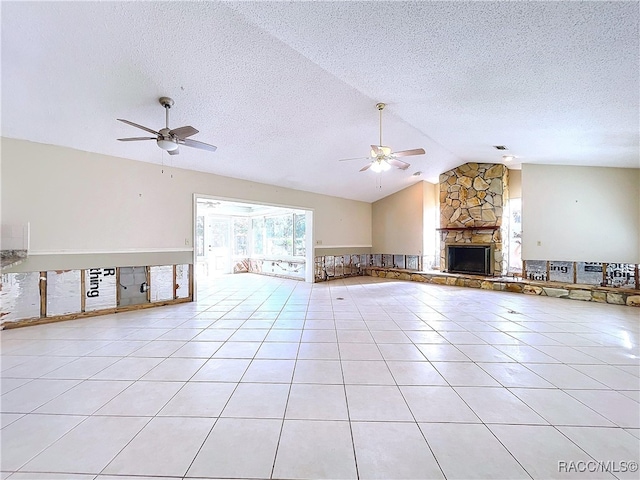 unfurnished living room with lofted ceiling, light tile patterned floors, ceiling fan, a fireplace, and a textured ceiling