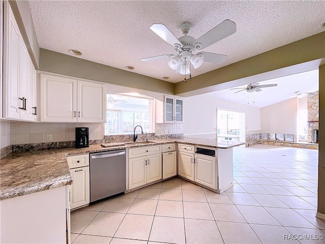 kitchen with sink, white cabinetry, light tile patterned floors, dishwasher, and kitchen peninsula