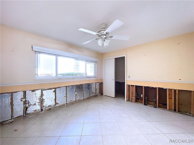 empty room with ceiling fan and a textured ceiling