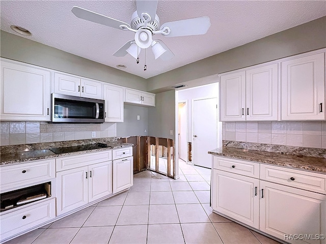 kitchen with white cabinets, black electric stovetop, and backsplash