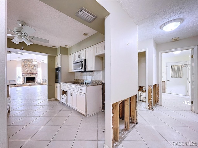 kitchen with appliances with stainless steel finishes, light tile patterned floors, white cabinets, and ceiling fan