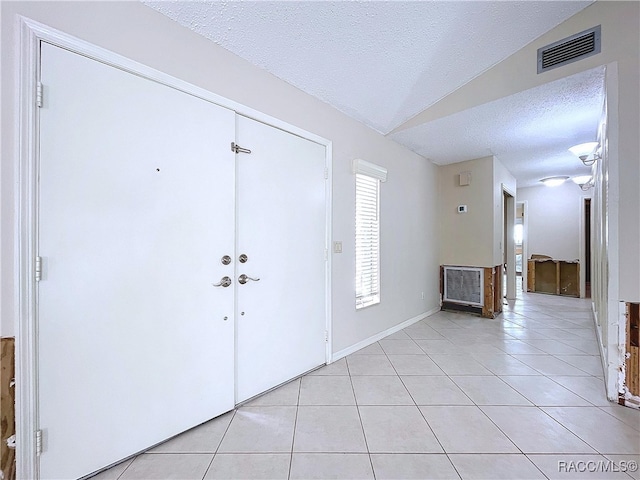 tiled entryway with lofted ceiling and a textured ceiling