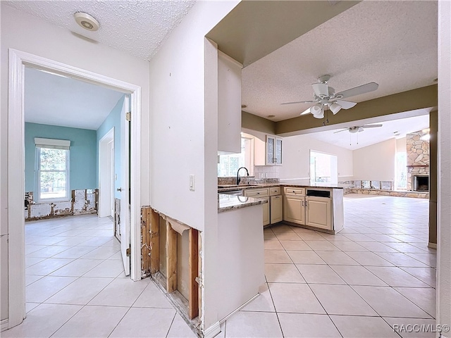 kitchen featuring light tile patterned floors, sink, a fireplace, a textured ceiling, and cream cabinetry