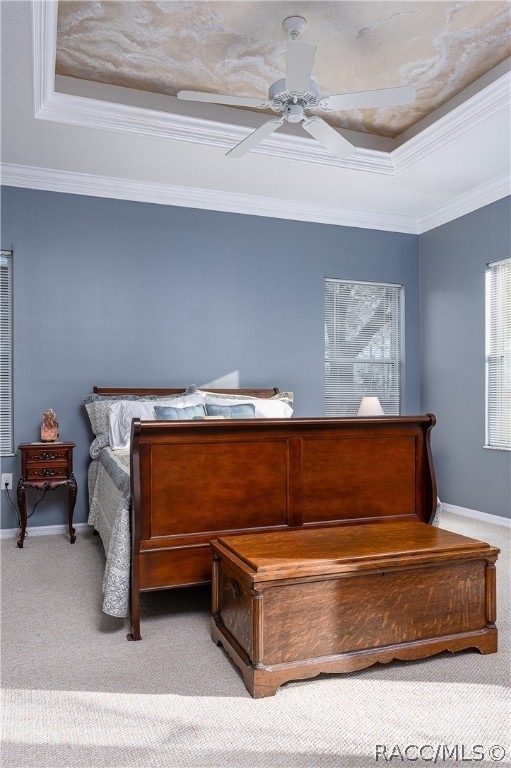 bedroom featuring light carpet, a tray ceiling, ceiling fan, and crown molding