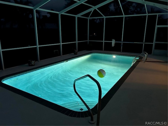 view of swimming pool with glass enclosure and a patio area