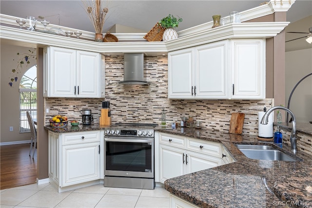 kitchen featuring sink, wall chimney exhaust hood, backsplash, dark stone counters, and stainless steel electric range