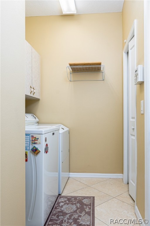 laundry area featuring cabinets, independent washer and dryer, and light tile patterned floors