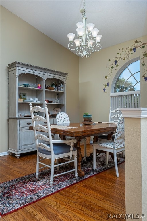 dining room featuring wood-type flooring, an inviting chandelier, and lofted ceiling