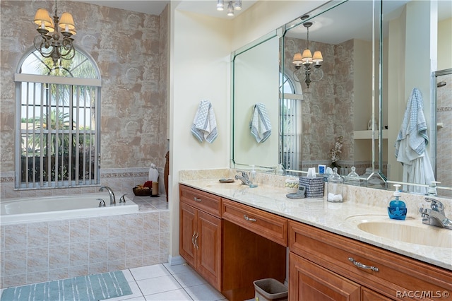 bathroom featuring tile patterned floors, vanity, an inviting chandelier, and tiled tub