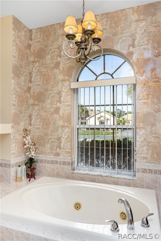 bathroom featuring a notable chandelier and a relaxing tiled tub