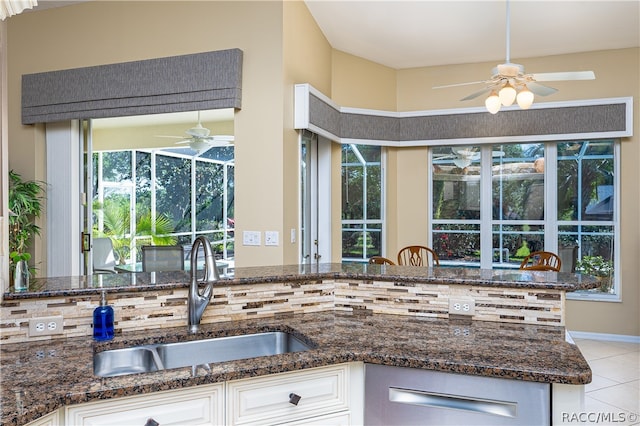 kitchen with hanging light fixtures, sink, dark stone countertops, light tile patterned floors, and white cabinetry