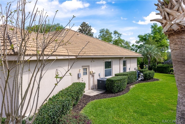 rear view of house featuring a lawn and cooling unit