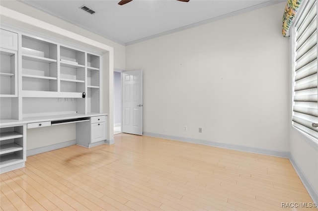 unfurnished office featuring ceiling fan, light hardwood / wood-style flooring, built in desk, and ornamental molding