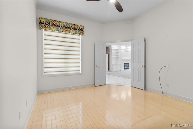 empty room featuring ceiling fan, light hardwood / wood-style floors, and crown molding