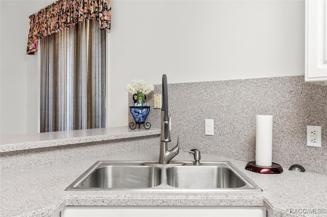 kitchen featuring tasteful backsplash, sink, and white cabinets