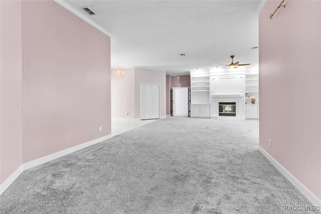 unfurnished living room with carpet flooring, ceiling fan with notable chandelier, and crown molding