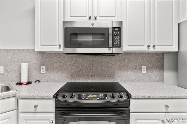 kitchen with decorative backsplash, white cabinetry, and black / electric stove