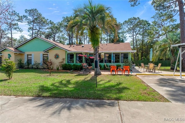 ranch-style home featuring a sunroom, a patio area, and a front yard