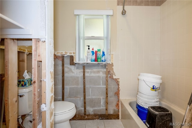 bathroom with tile patterned floors, toilet, tile walls, and a bathing tub