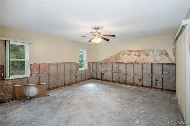 unfurnished room with a wealth of natural light, ceiling fan, and a textured ceiling