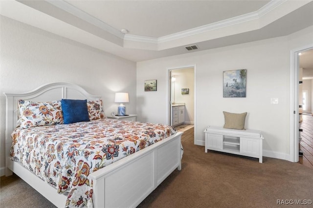 carpeted bedroom with a tray ceiling, crown molding, visible vents, and baseboards