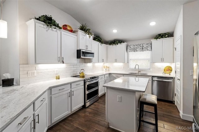 kitchen with dark wood finished floors, appliances with stainless steel finishes, white cabinetry, and a sink