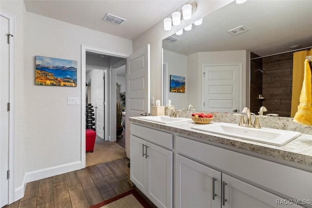 full bath with a sink, visible vents, wood finished floors, and double vanity