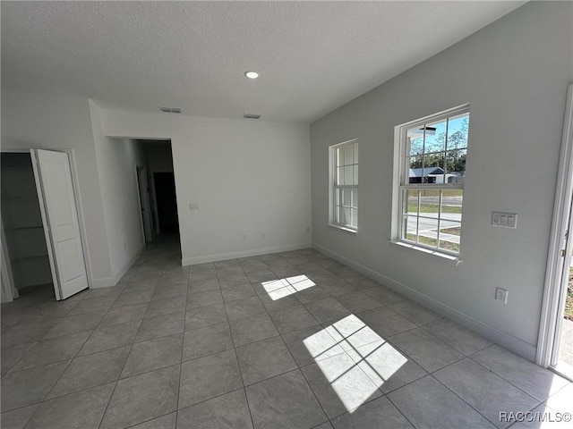 spare room with light tile patterned floors and a textured ceiling