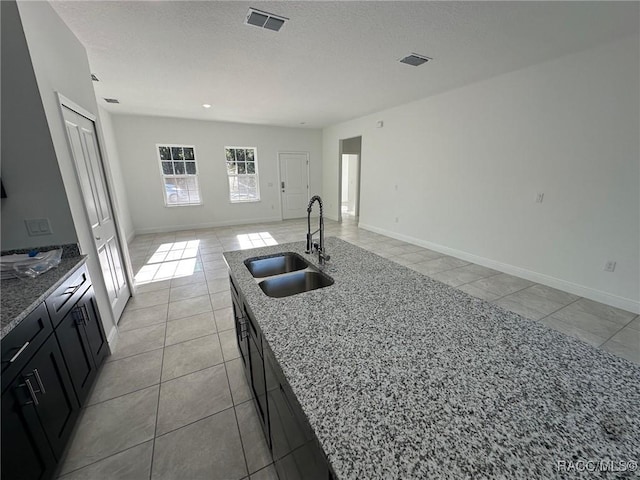 kitchen with light stone counters, sink, and light tile patterned flooring