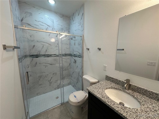 bathroom with tile patterned floors, vanity, toilet, and a shower with door