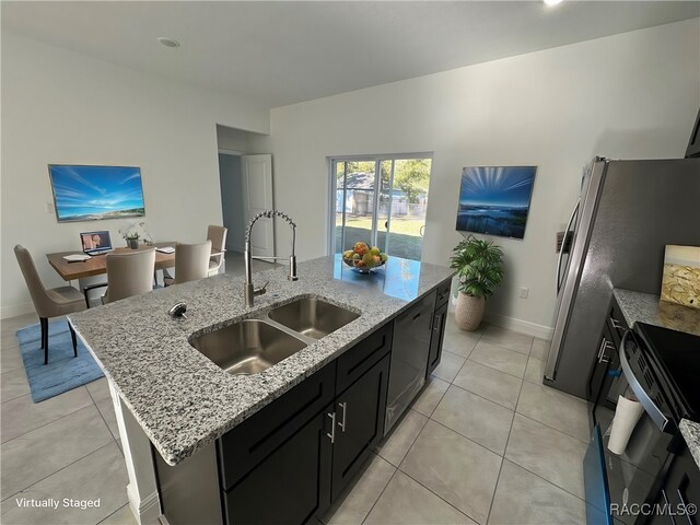 kitchen featuring dishwashing machine, light stone counters, a kitchen island with sink, and sink