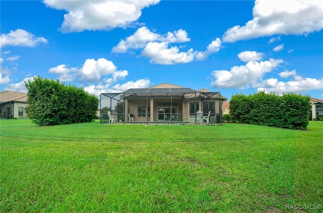 rear view of property featuring a lawn and glass enclosure