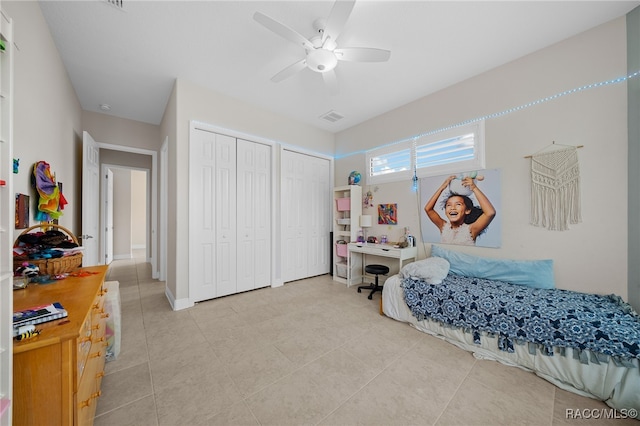 tiled bedroom featuring ceiling fan and multiple closets