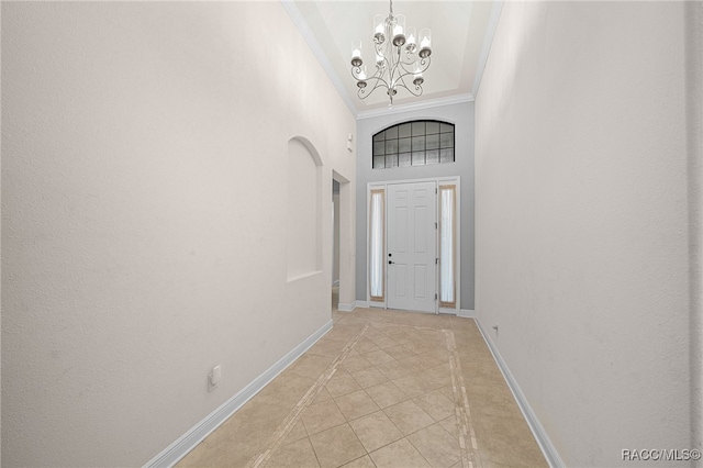 tiled entryway with crown molding, a chandelier, and a high ceiling