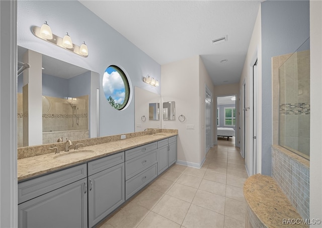 bathroom with tile patterned flooring, vanity, and tiled shower