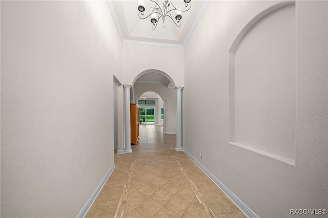 hallway with a chandelier, light tile patterned floors, decorative columns, and crown molding