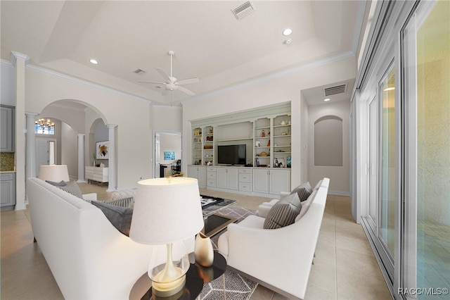 living room featuring ceiling fan, built in features, light tile patterned floors, a tray ceiling, and decorative columns