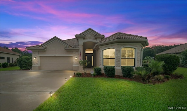 mediterranean / spanish-style house with an attached garage, a front lawn, a tile roof, stucco siding, and driveway