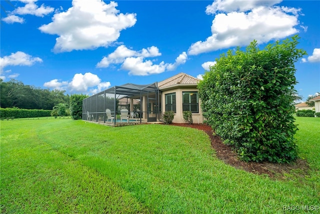 rear view of house with a tiled roof, glass enclosure, stucco siding, a yard, and an outdoor pool