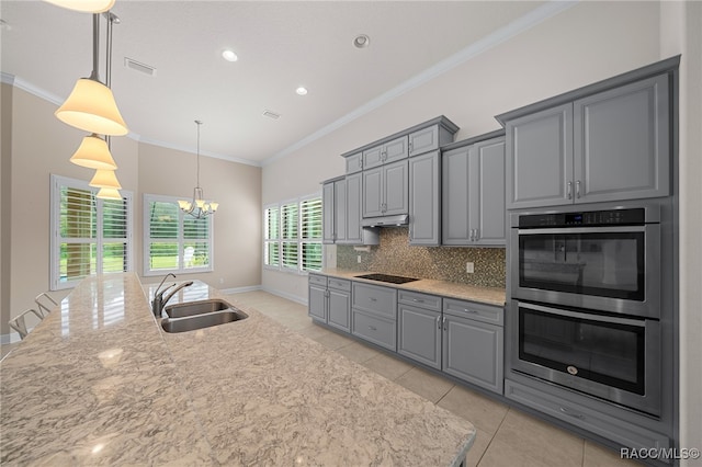 kitchen featuring backsplash, gray cabinets, a notable chandelier, stainless steel double oven, and a sink