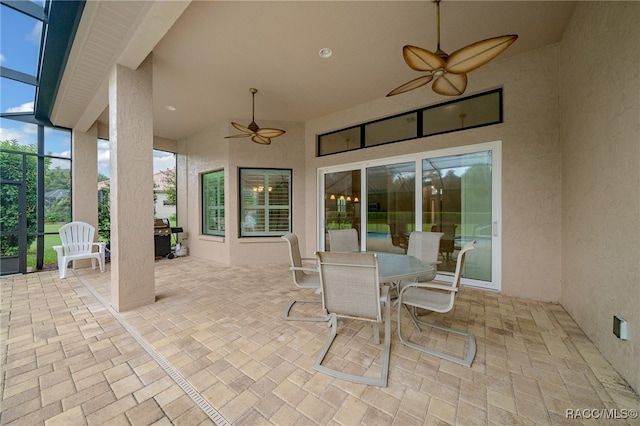 view of patio featuring a lanai, area for grilling, outdoor dining area, and ceiling fan