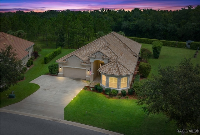 view of front facade with stucco siding, driveway, an attached garage, and a front lawn