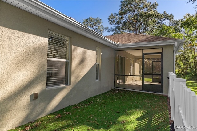 view of side of property with a lawn and a sunroom