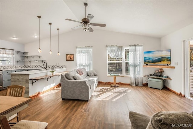 living room with wood-type flooring, ceiling fan, lofted ceiling, and sink