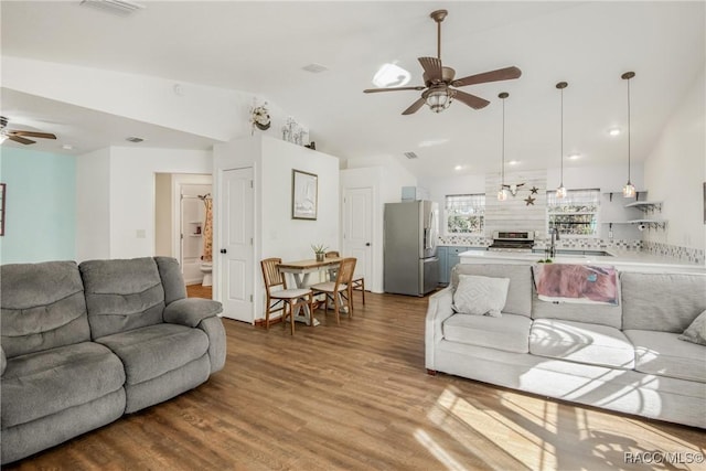 living room featuring wood-type flooring, vaulted ceiling, ceiling fan, and sink