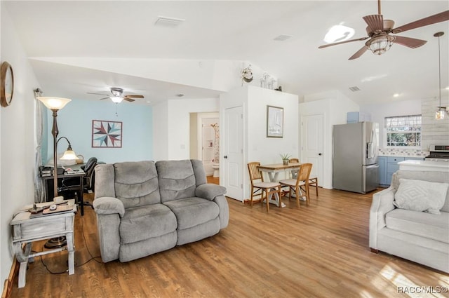 living room with light hardwood / wood-style floors, vaulted ceiling, and ceiling fan